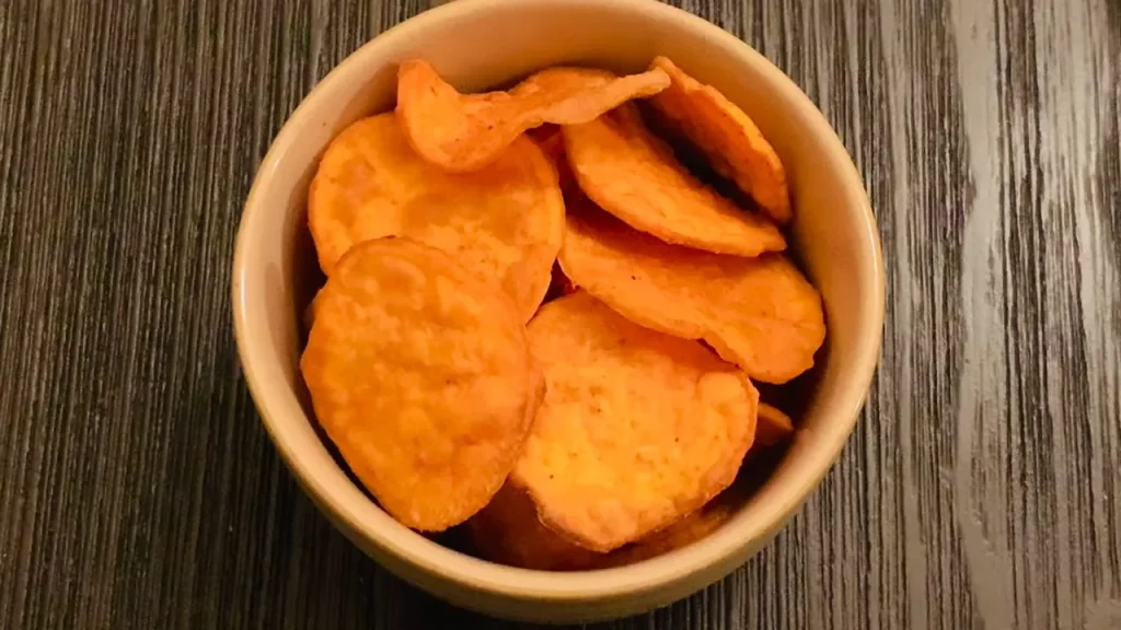 Fatias finas de batata doce temperadas, preparadas para cozinhar na air fryer e transformar-se em deliciosos chips.